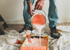 Ouvrier en train de verser un pot de peinture rose dans un bac de peinture
